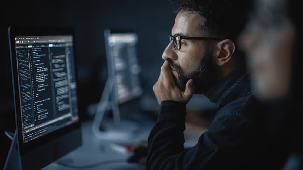 IT engineer looks at his computer while coding.